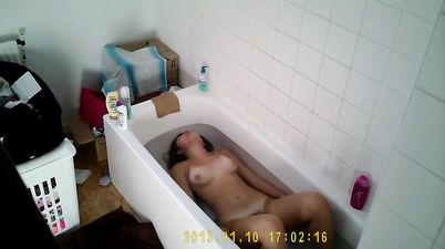 Brunette soaks her big tits and bush in the tub